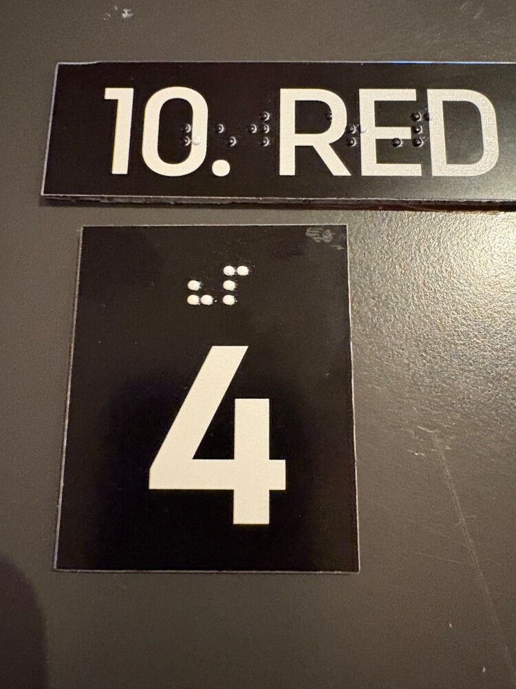 Oznaka 10. reda i sjedala 4 s brojevima i Brailleovim pismom